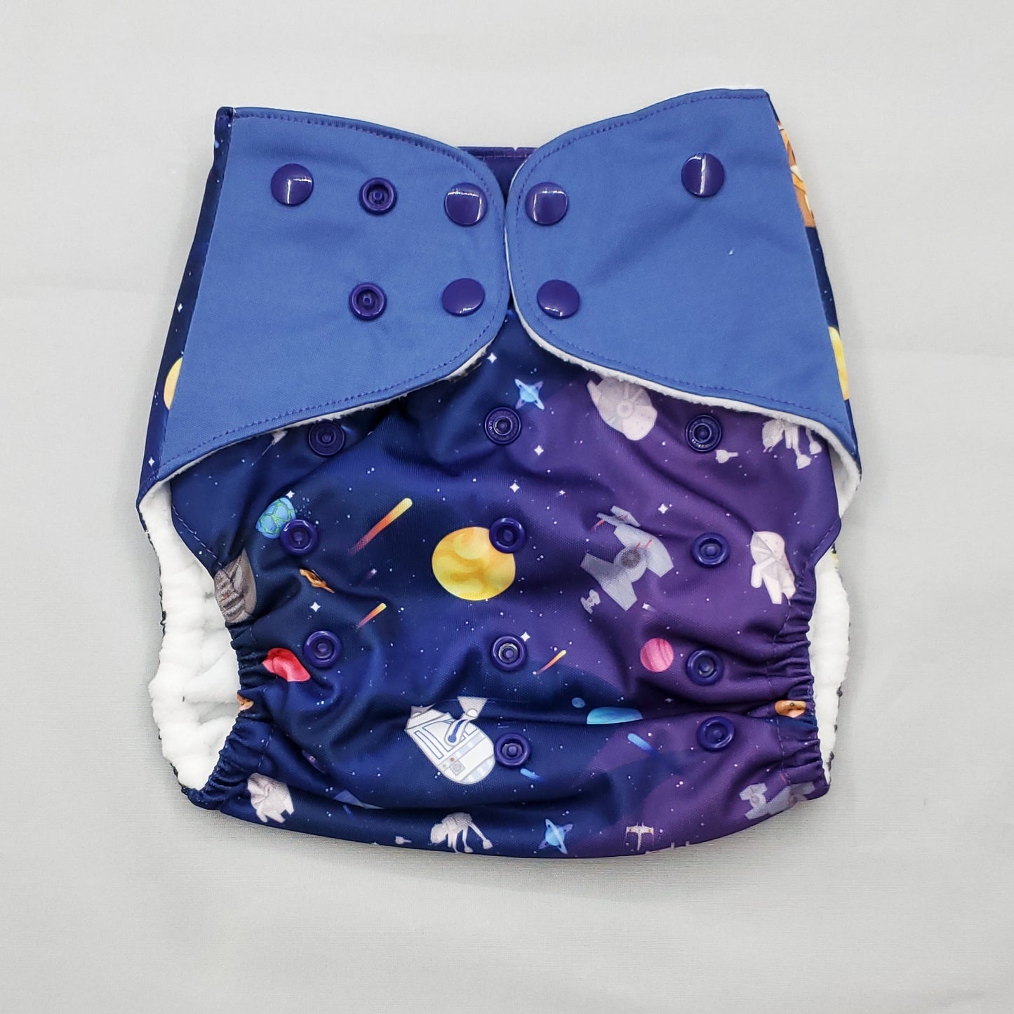 cloth diaper with extended size range of 20-60+lbs.  A modern cloth diaper with a fandom-inspired design inpired by star wars and space